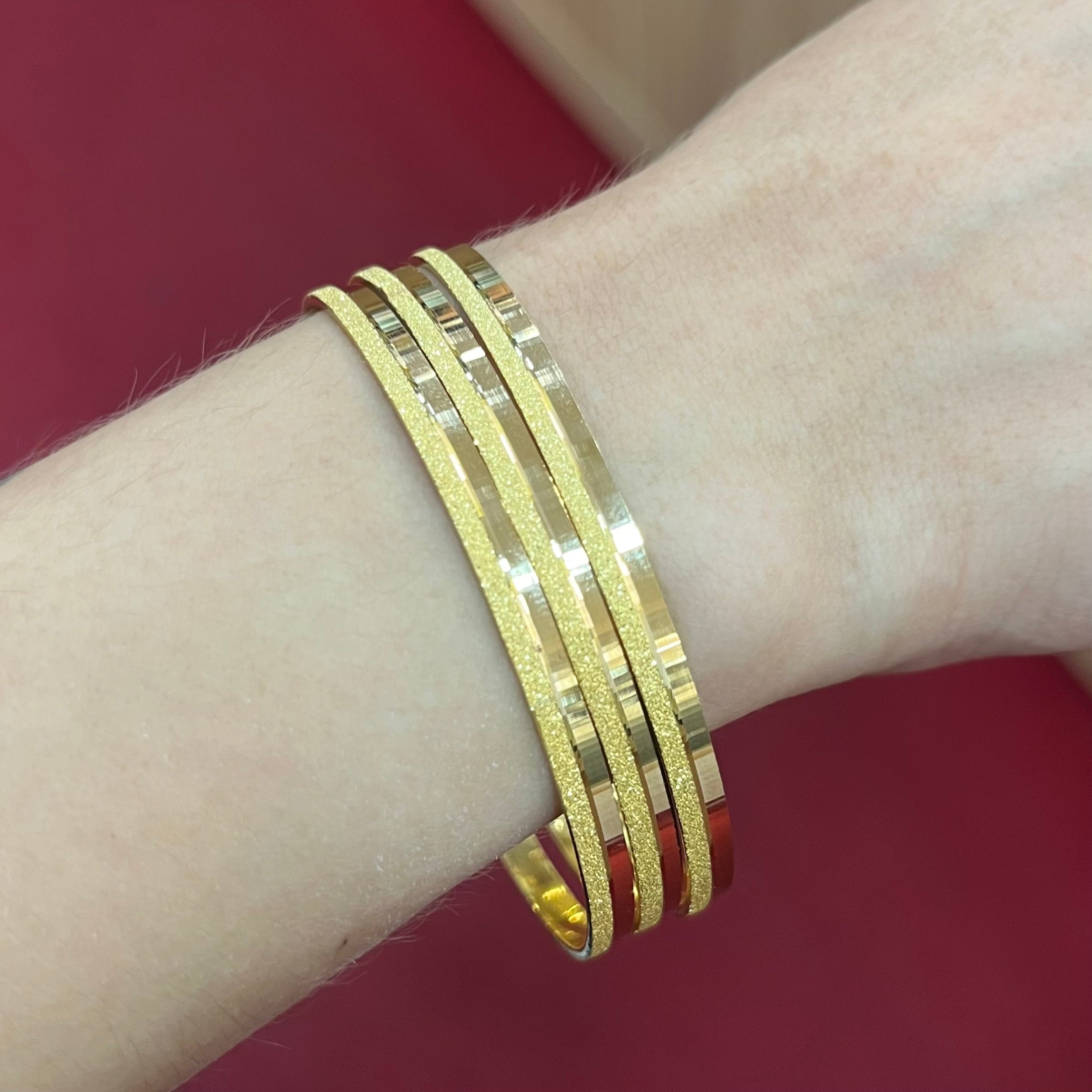 Kombinierte 22K Gold Armreifen im Simli Ray Design mehrfach gestapelt getragen