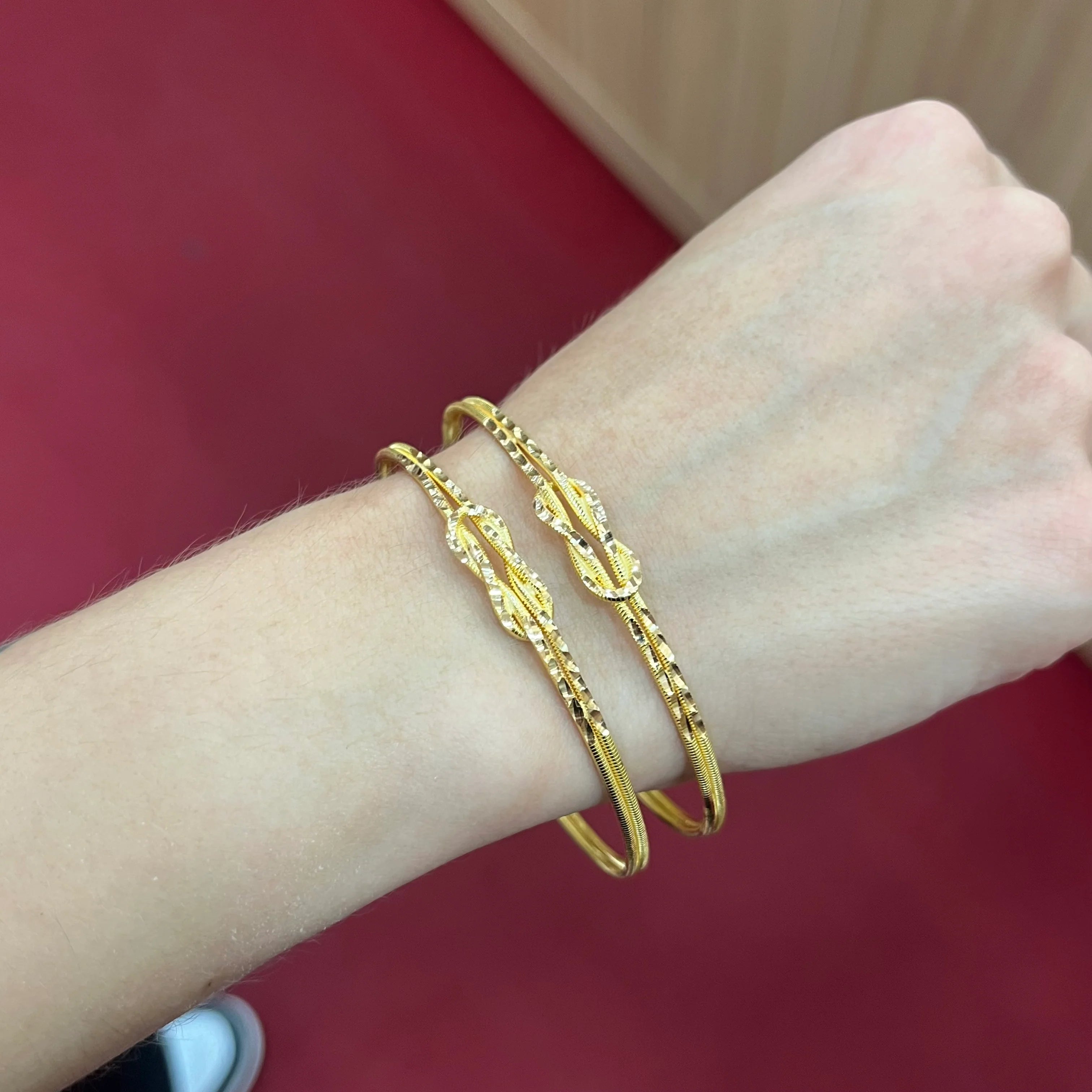 Mehrere 916 Liebesknoten Armreifen aus 22 Karat Gelbgold stilvoll kombiniert am Handgelenk getragen